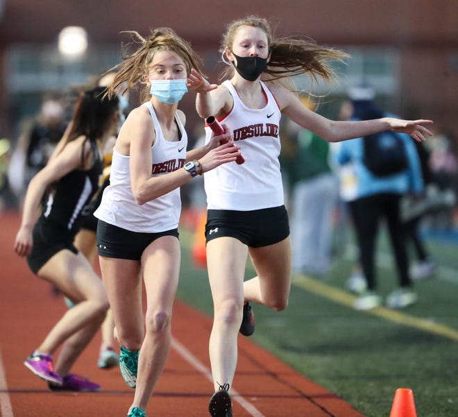 Ursuline's Ragan Odle (right) hands off to Bella Lindia as they help their team to a win in the 4x400 meter relay during the DIAA state indoor track and field championships at Dover High School Wednesday, March 3, 2021.